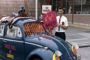 Dick Baker with a VW Beetle promoting the Yard Birds Bakery