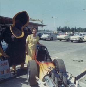 Ann Helena posing with a Yard Birds statue and the sponsored dragster